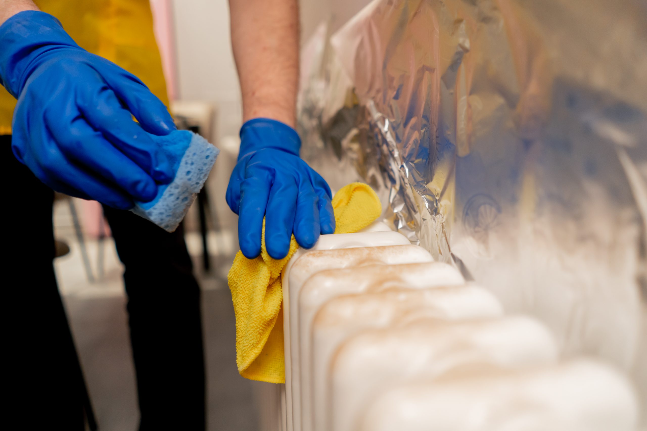 close up in an apartment cleaner in a yellow apron washes a white iron battery from rust